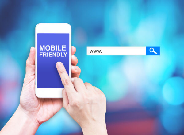 Hand touch mobile phone with  mobile friendly word with search box at blurred blue background, Digital marketing business concept.