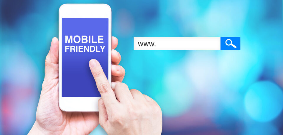 Hand touch mobile phone with  mobile friendly word with search box at blurred blue background, Digital marketing business concept.